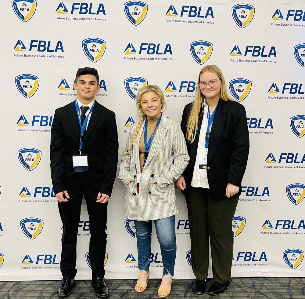 Lexi Burroughs, Bryce Branscum, and Brylen Miller standing in front of an FBLA banner  